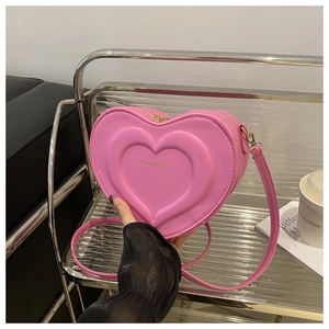 Close-up of heart-shaped crossbody bag in bright pink with embossed details