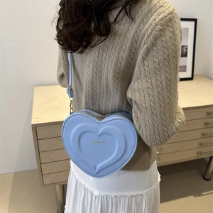 Light blue heart shaped crossbody bag with embossed patterns and adjustable strap