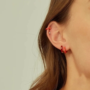 Colorful round hoop earrings with red enamel and zircon crystals set on model's ear