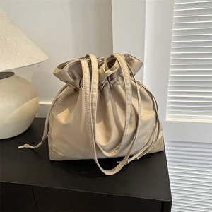Minimalist beige drawstring tote bag with suede bottom for women in cozy indoor setting