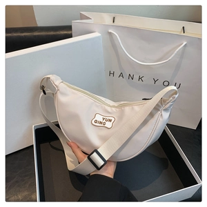 Detail of off-white crescent crossbody bag with YUN QING label and adjustable wide strap