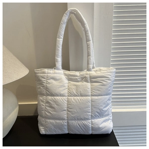 Detail of white quilted down fabric tote bag with thick padded handles and square stitching