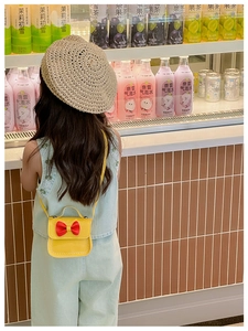 Sac bandoulière jaune pour fille avec nœud rouge, porté par un enfant en gros plan