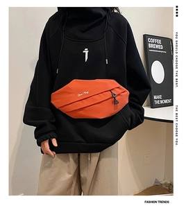 Detail view of the black oversized hoodie with functional orange integrated chest pocket