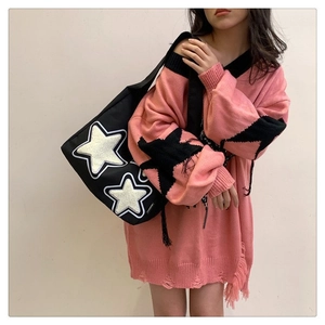 Detail view of a black canvas tote featuring two white plush stars with contrast stitching