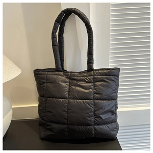 Detail shot of large square quilted stitching on a black down-filled cotton tote bag