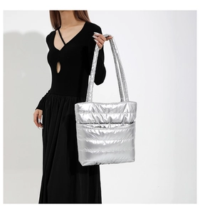 Macro shot of silver quilted tote bag featuring a high-gloss metallic finish and open front pocket
