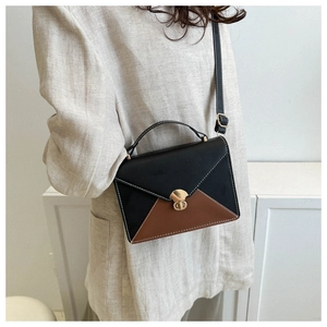 Modèle portant un sac bandoulière enveloppe bicolore en similicuir noir et marron