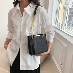 Detail of black quilted shoulder bag featuring gold chain and textured rhombus pattern