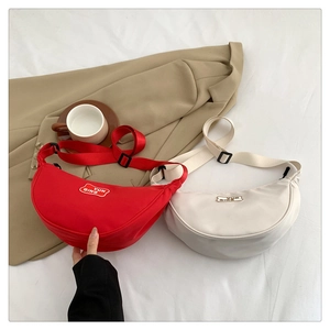 Chic red and beige canvas crescent bags displayed on a clean white background with props