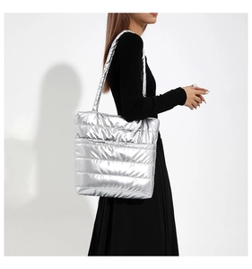 Detailed macro view of silver quilted tote bag with metallic padded stitch texture