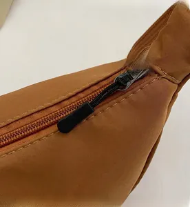Dettaglio di una borsa a tracolla marrone in nylon con zip robusta e tiranti in corda nera