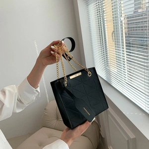 Detailed view of black quilted crossbody bag with gold chain strap and leather tag