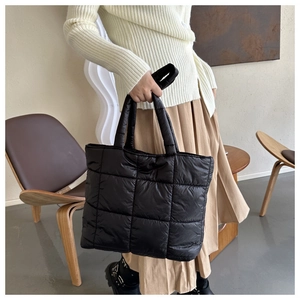 Detail view of black quilted puffer tote bag with puffy texture and stitched pattern