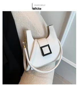 Detail of white lychee leather square bag with black buckle and gold chain strap