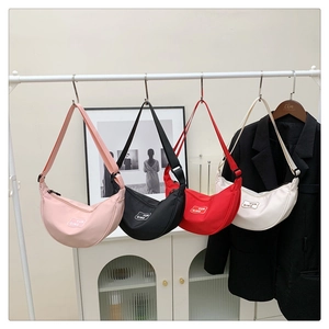 Detailed view of half-moon nylon crossbody bags in pink, black, red, and beige colors