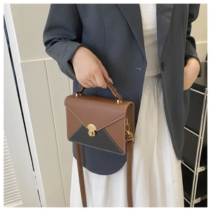 Détail du sac enveloppe bicolore avec fermoir doré et bandoulière réglable pratique