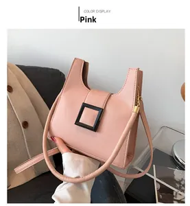 Detailed close-up of a pink crossbody bag featuring a large black square buckle design