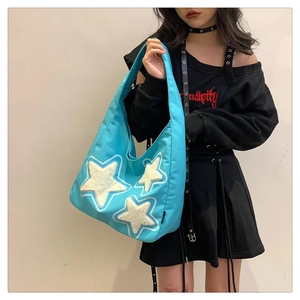Detail of light blue tote bag with white plush stars on nylon fabric worn by model