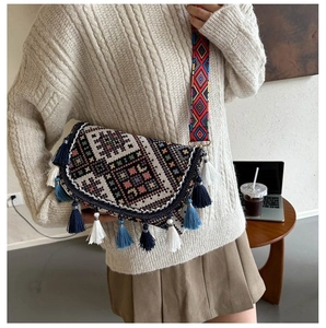 Detail of ethnic crossbody bag with bohemian embroidery, colorful tassels and woven strap