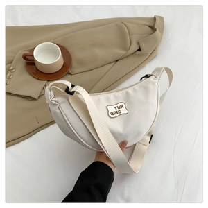 Detail of white nylon crescent bag with adjustable wide strap and YUN QING logo