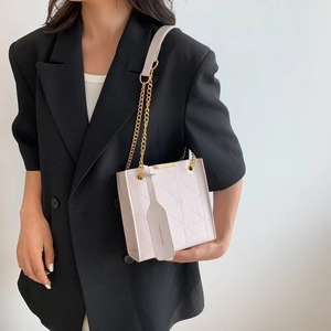 Close-up of white quilted leather texture and golden chain strap on stylish shoulder bag