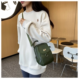Detail view of mini green Oxford nylon shoulder bag with dual zipper and hardware