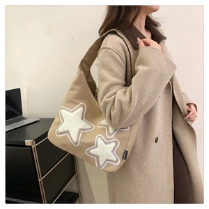 Detail of khaki tote bag with plush cream star patches and high-density nylon texture