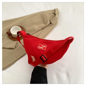 Detail view of red canvas crescent bag with YUN QING letter patch and adjustable strap