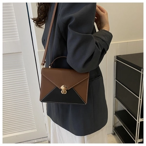 Vue détaillée d'un sac bandoulière bicolore avec serrure dorée ronde et coutures blanches fines