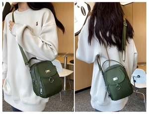 Detail view of a dark green nylon mini crossbody bag with multiple zipper compartments