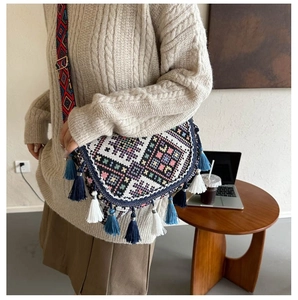 Detail view of ethnic crossbody bag with geometric weave, colorful tassels and wide strap