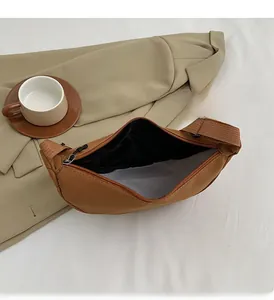 Vista macro degli interni capienti della borsa a tracolla in nylon marrone con cerniera