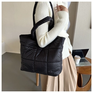 Close-up of black quilted tote bag texture and reinforced handles in a cozy lifestyle setting