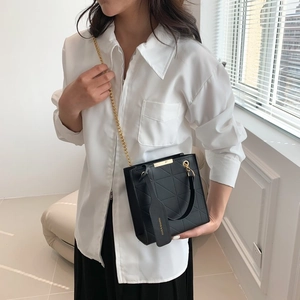 Chic black quilted handbag with elegant gold chain and fashion tag displayed on model