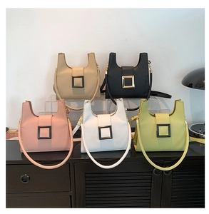 Group view of stylish small square handbags in multiple colors on a wooden shelf