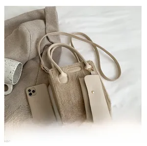 Close-up of khaki plush tote bag with a matching small pouch and a metal logo plaque
