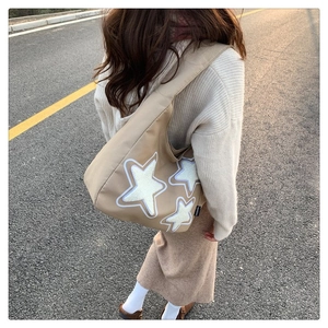 Close-up of khaki canvas tote with star embroidery and side fashion tag in sunset light