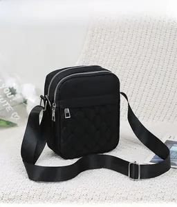 Detail of black nylon crossbody bag with diamond quilted stitching and zip compartments
