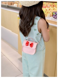 Sac rose pour fille avec nœud rouge, porté avec un chapeau et une robe bleue