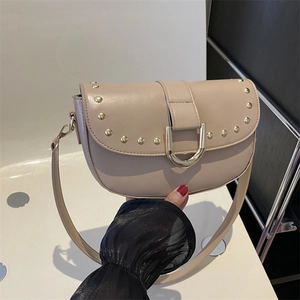 Sac bandoulière beige avec clous dorés et boucle en D, doté d'une sangle réglable