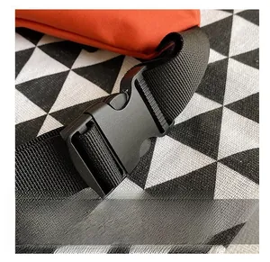 Detail of durable black plastic buckle and high-density nylon strap on orange bag