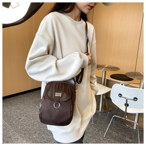 Detail of dark brown nylon mini crossbody bag showing silver hardware and fabric strap