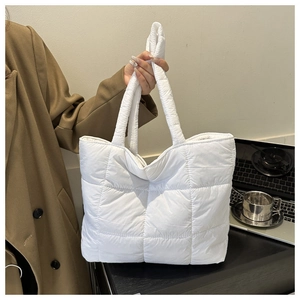 Detail of white quilted tote bag with padded shoulder straps and knot design