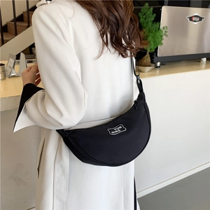 Minimalist black half-moon crossbody bag with adjustable strap and logo patch