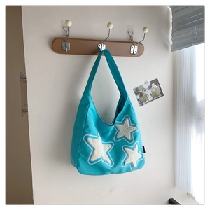 Detail of bright blue canvas tote bag with three plush white star patches on wooden hook