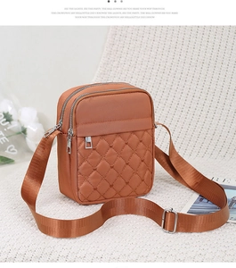 Detail view of caramel quilted nylon crossbody bag with multi-layer zipper compartments