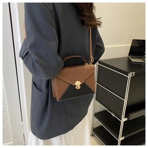 Détail du sac enveloppe bicolore avec surpiqûres blanches et fermoir anneau doré