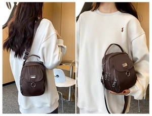 Detail of a dark brown nylon crossbody bag with double zipper and silver metal ring decoration