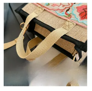 Detail presentation of floral embroidery and gold metal hooks on an ethnic tote bag